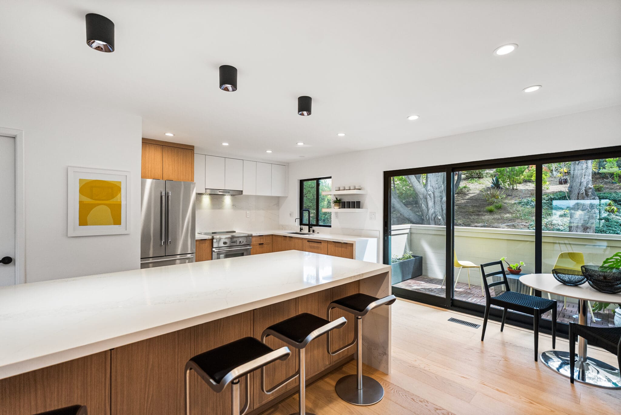 Modern open concept kitchen featuring a large waterfall island and black stools.